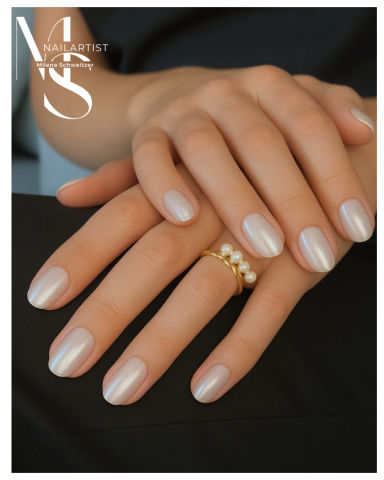 Zwei Hände mit eleganter, heller Nagelfarbe und einem Ring mit Perlen.